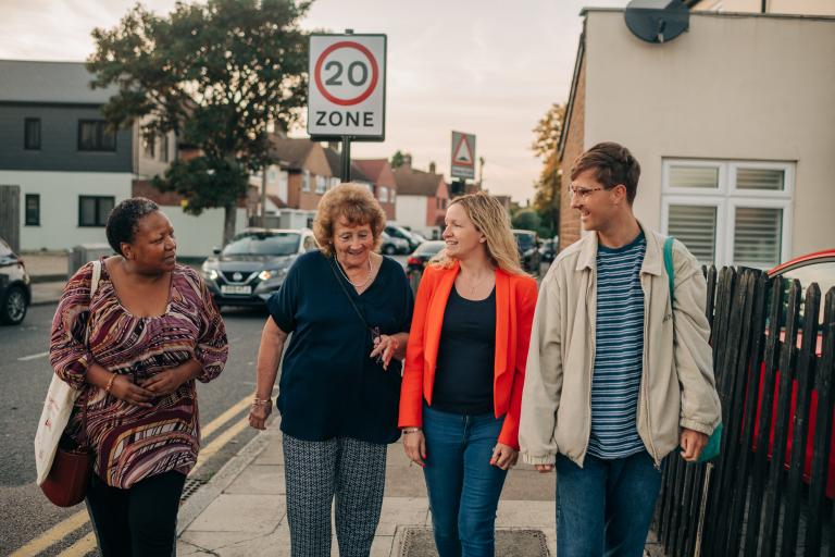4 people walking down a residential street in Greenwich